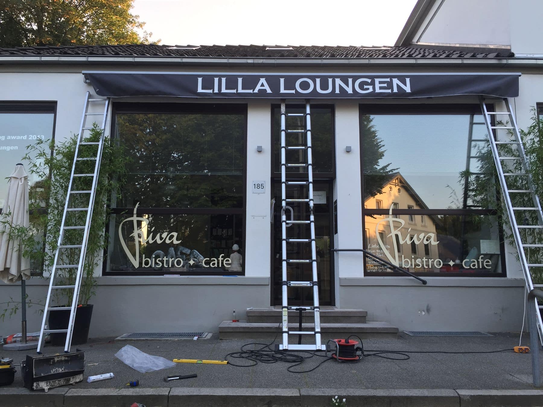 Im „Lilla Loungen Riva Bistro-Café“ laufen Installations- oder Wartungsarbeiten, vor dem Lokal sind Leitern und Werkzeuge vorhanden.