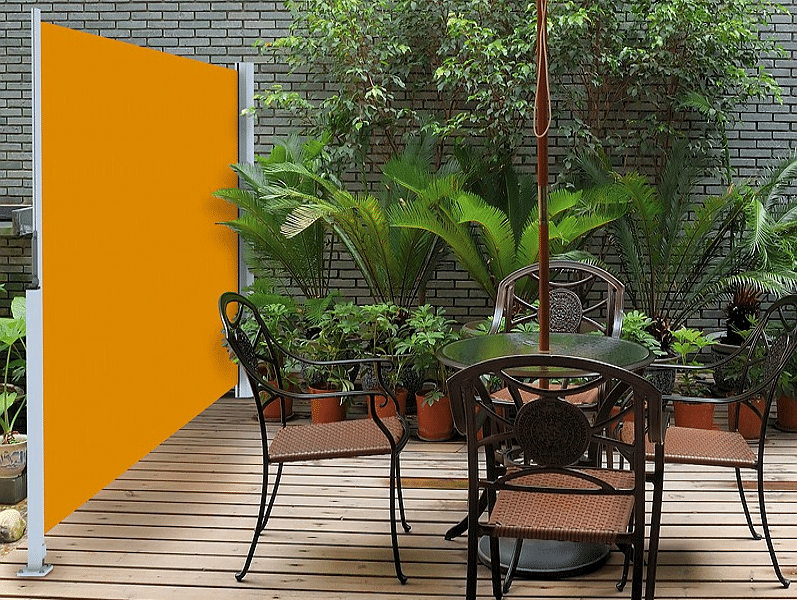 Gemütlicher Terrassenbereich im Freien mit üppigen grünen Pflanzen und schmiedeeisernen Möbeln.